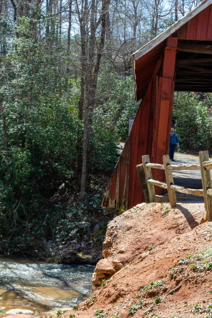 An old red covered bridge over a rocky river