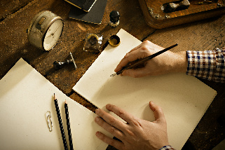 A writer working on a longhand manuscript with several sharp pencils waiting and a clock keeping time.
